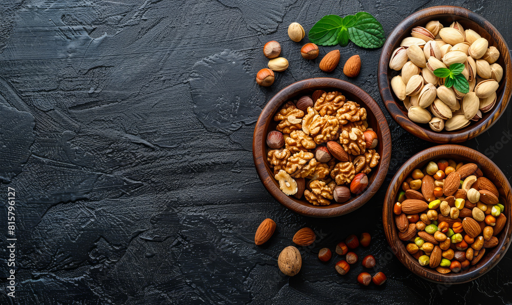 Fototapeta premium Wooden Bowl Filled With Assorted Mixed Nuts - Almonds, Pistachios, Walnuts, Cashews, Hazelnuts On Black Stone Table Top View