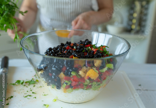 Woman preparing a healthy vegan salad with rice, beans, fruit and vegetables