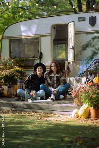 A duo of chic ladies flaunt their bohemian flair in front of the trailer.