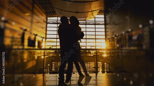 Silhouette of man and a woman meeting in airport terminal or train station after arrival. People hugging. Concept of travel, tourism and transport. Long-awaited meeting. Sunset panoramic window.