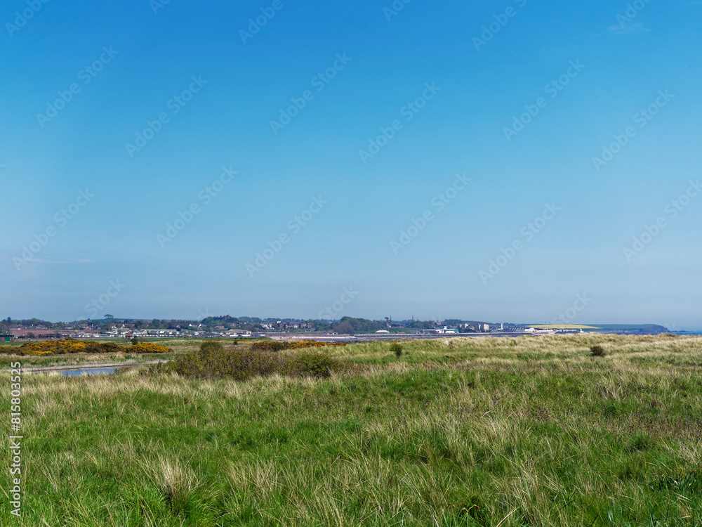 Looking over the grass covered raised Beach behind Elliot Beach to the south of Arbroath which is seen in the distance. Looking over the grass covered raised Beach behind Elliot Beach to the south of Arbroath which is seen in the distance.