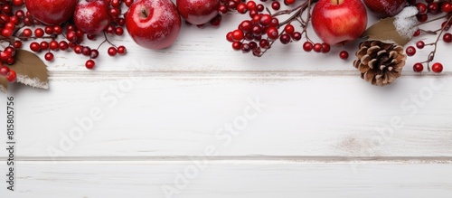 A festive Christmas scene with a white wooden background adorned with vibrant red apples ranetka and viburnum berries The composition leaves ample copy space for adding text making it perfect for hol photo