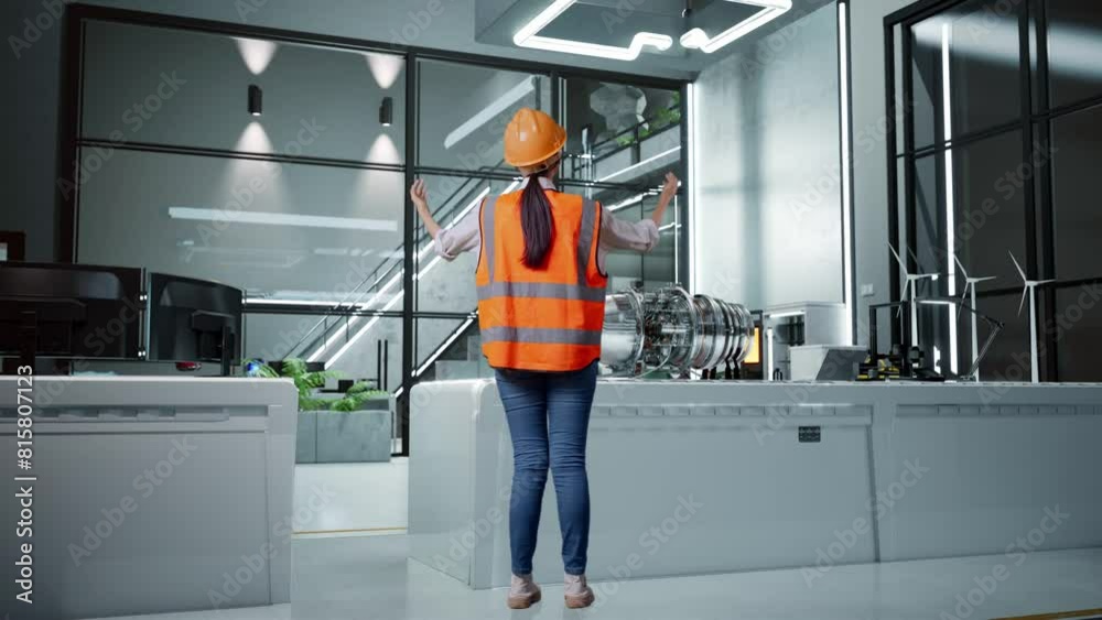 Back View Of A Female Engineer With Safety Helmet Spreading Arms While Standing With Electric Engine for Innovative Project Back View Of A Female Engineer With Safety Helmet Spreading Arms While Standing With Electric Engine for Innovative Project