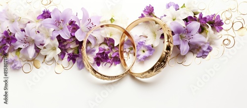 A marriage symbol two wedding rings rest on a pristine white backdrop while lovely white and purple flowers adorn the periphery evoking devotion and affection Ample room for custom graphic photo