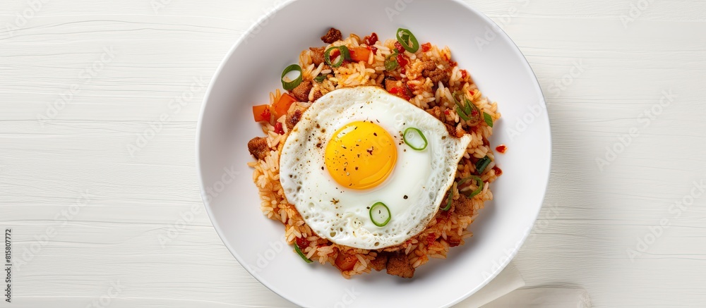 A top view of a Korean dish kimchi fried rice served in a bowl on a white table garnished with a fried egg Perfect for a copy space image A top view of a Korean dish kimchi fried rice served in a bowl on a white table garnished with a fried egg Perfect for a copy space image