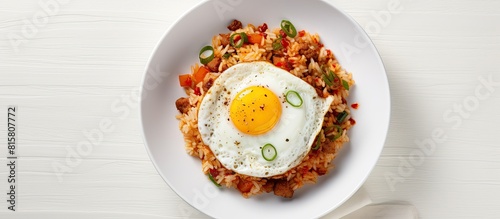 A top view of a Korean dish kimchi fried rice served in a bowl on a white table garnished with a fried egg Perfect for a copy space image