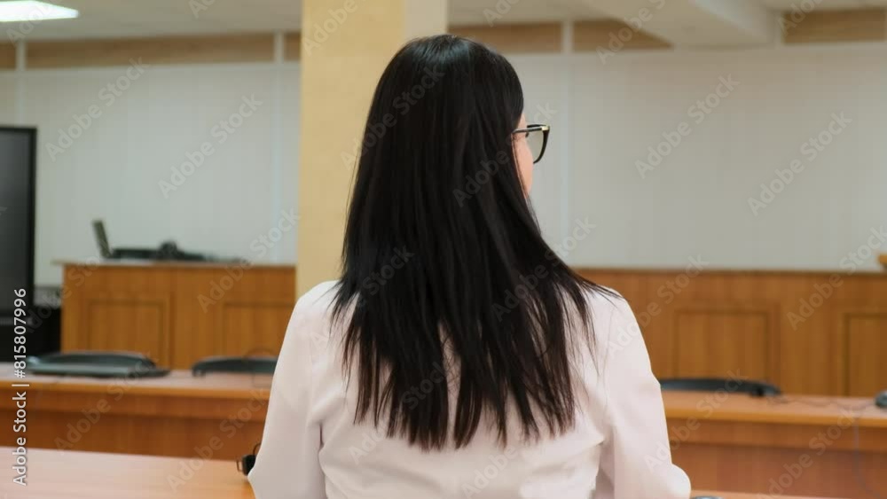 Woman doctor in white gown works on laptop. Back view Woman doctor in white gown works on laptop. Back view