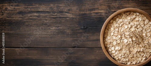 Top view of a wooden bowl filled with organic oat flakes creating a healthy breakfast option Ample copy space provided
