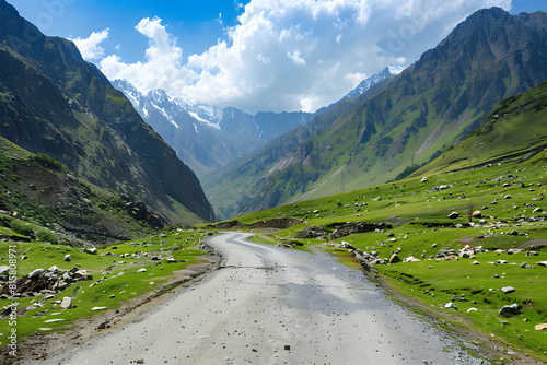 Winding road through lush green valleys against a backdrop of majestic mountains