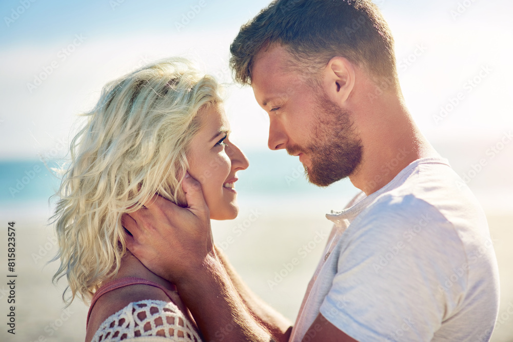 Obraz premium Smile, couple and holiday on beach with love for seaside romance, serene seascape and ocean view with affection. Man, woman and together for bonding by coast on weekend date, embrace and hug
