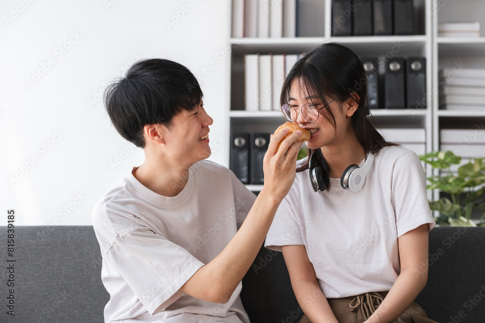 Young couple sitting together on the sofa in the living room Have coffee and snacks together. Young couple sitting together on the sofa in the living room Have coffee and snacks together.