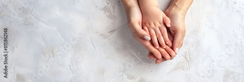 Closeup above view loving mother holds hand of child baby on grey background. Copy space. Banner happy family. Love, support, protection of children, adoption, childhood, maternal affection, childcare