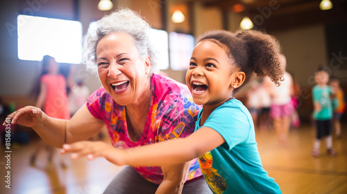 An older woman and a young girl joyfully dancing together in a gym during a Zumba class, showcasing intergenerational connection and movement photo