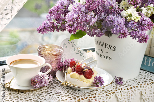 Meringue cake, coffee and bunch of purple lilacs on the windowsill © teressa