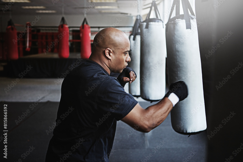 Exercise, punching bag and man in MMA gym for boxing, challenge or competition training. Power, muscle and serious champion boxer at workout with confidence, fight and energy in sports fitness club. Exercise, punching bag and man in MMA gym for boxing, challenge or competition training. Power, muscle and serious champion boxer at workout with confidence, fight and energy in sports fitness club.