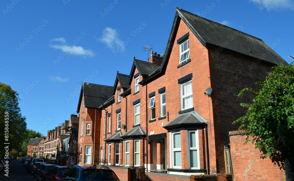 Fototapeta premium a typical English small town street with narrow terraced, adjoining red brick houses with bay windows