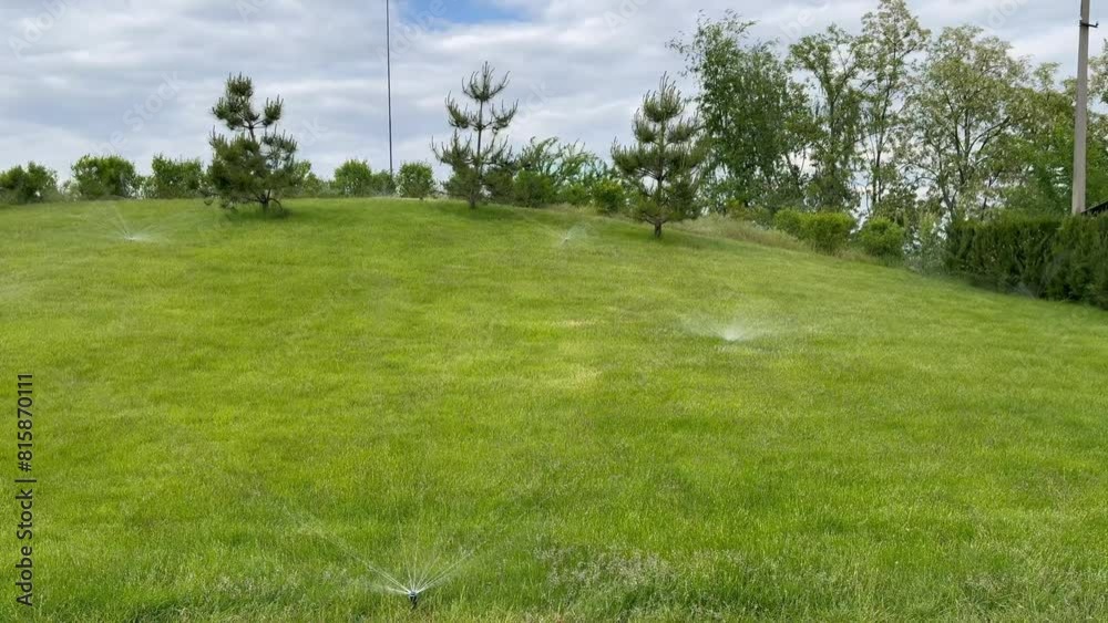 Lawn watering cans turn around and water the green grass in the park Lawn watering cans turn around and water the green grass in the park
