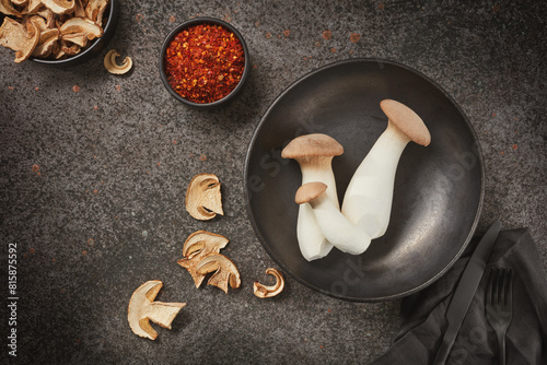 King Oyster mushrooms or Eringi in a bowl and dried white mushrooms on a dark background. Flat lay.