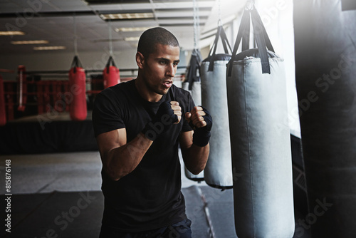 Power, punching bag and man in boxing ring for workout, challenge or competition training. Fitness, muscle and strong champion boxer in exercise with confidence, fight and energy in MMA sports club. © peopleimages.com