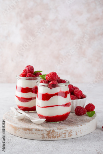 Vanilla white chocolate mousse, trifle, panna cotta or parfait with raspberry sauce in a glass jar. Sweet summer dieting dessert.