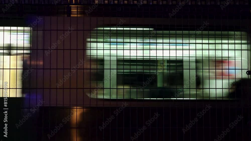 Close-up view of a train's interior lit by soft artificial light, viewed through a window with a metal grid at night. Close-up view of a train's interior lit by soft artificial light, viewed through a window with a metal grid at night.