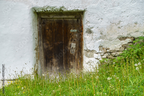 Eine alte dunkle Holztür in rustikalem Gemäuer als idealer Hintergrund