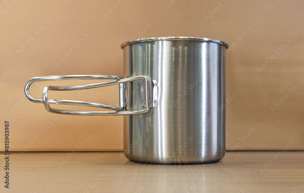 Iron cup on the table. Silver metallic travel cup, brown background. Leisure and travel concept. Iron cup on the table. Silver metallic travel cup, brown background. Leisure and travel concept.