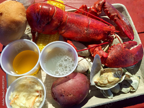 Lobster meal with clams, corn, drawn butter, coleslaw, and biscuit photo