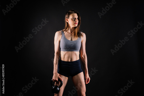 Attractive young athlete with muscular body exercising crossfit workout with kettlebell.