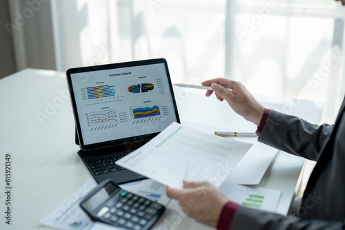 A man is pointing at a laptop screen with a graph on it