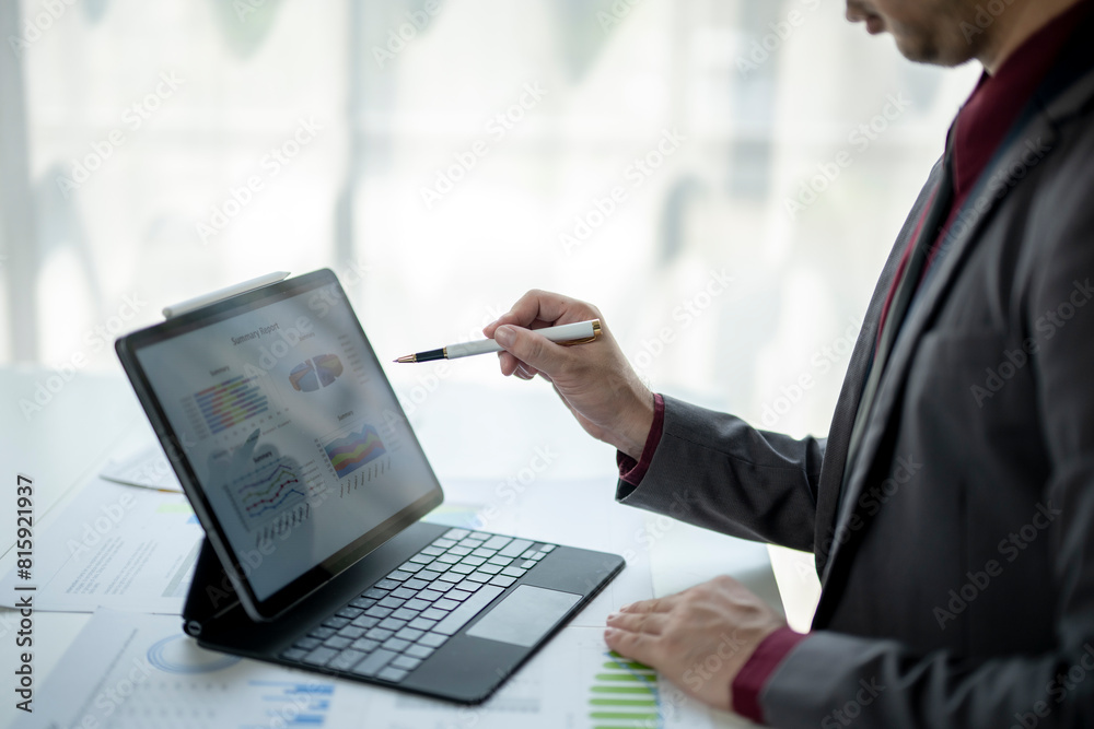 A man is sitting at a desk with a laptop and a white pen A man is sitting at a desk with a laptop and a white pen