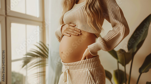 Young woman pregnant, close-up at belly, warm mood and tone.
