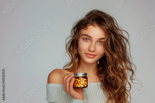 captivating gaze and healthy-looking hair, a young woman features prominently in a commercial photo as she proudly holds a jar of daily vitamin capsules supplements for iron defici