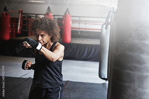 Fitness, punching bag and mature woman in boxing ring for gym, challenge or competition training. Power, muscle and champion boxer at workout with confidence, fight and energy in MMA sports club. © peopleimages.com