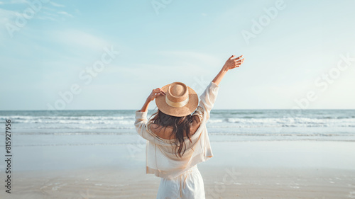 Summer beach vacation concept, Happy young woman with hat relaxing with her arms raised to her head enjoying looking view of beach ocean on hot summer day, copy space