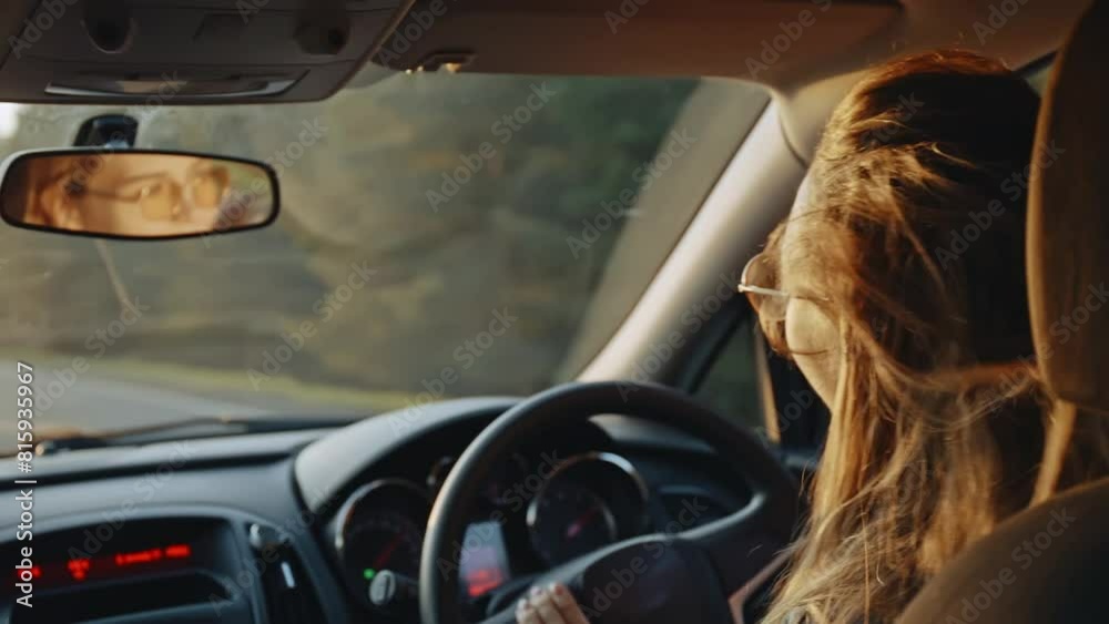 Rear view of happy young blonde in stylish sunglasses dancing to the music while driving her car at sunset. Pretty woman listening to enegetic music and smiling. Concept of joy and happiness Rear view of happy young blonde in stylish sunglasses dancing to the music while driving her car at sunset. Pretty woman listening to enegetic music and smiling. Concept of joy and happiness