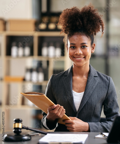 African american lawyer woman in suit holding envelope of business contract while sitting to working