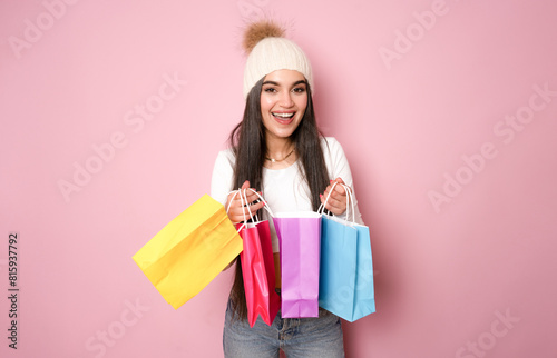 beautiful brunette young woman posing with shopping bags, isolated on pink background