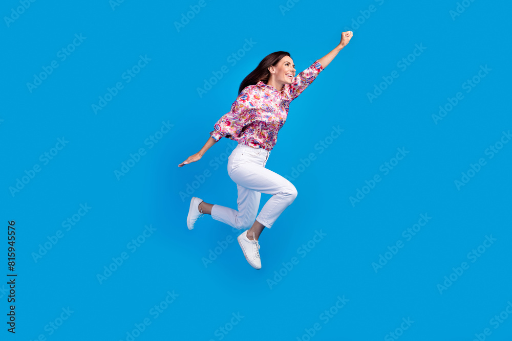 Full length photo of excited funky lady dressed print blouse jumping high hurrying empty space isolated blue color background Full length photo of excited funky lady dressed print blouse jumping high hurrying empty space isolated blue color background