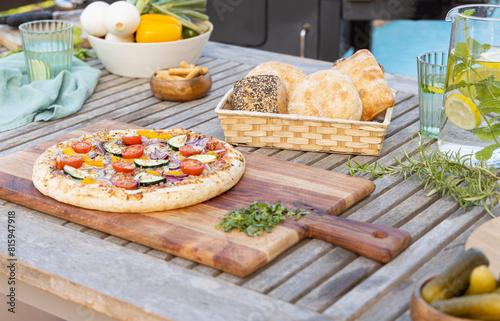 Homemade pizza with vegetables, on outdoor garden table..