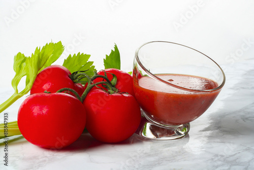 Tomatoes on branch and glass of tomato juice on marble background..
