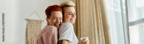 Two women with short hair embrace lovingly in front of a window, showcasing the beauty of their connection. photo