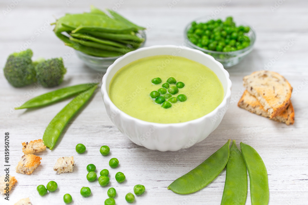 Cream soup with green pea on white wooden background.. Cream soup with green pea on white wooden background..