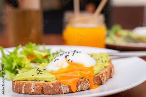 Delicious breakfast. Whole Wheat Toast with Avocado Cream topped with a Poached Egg. Toast with avocado cream and poached egg on top. selective focus. Soft focus.
