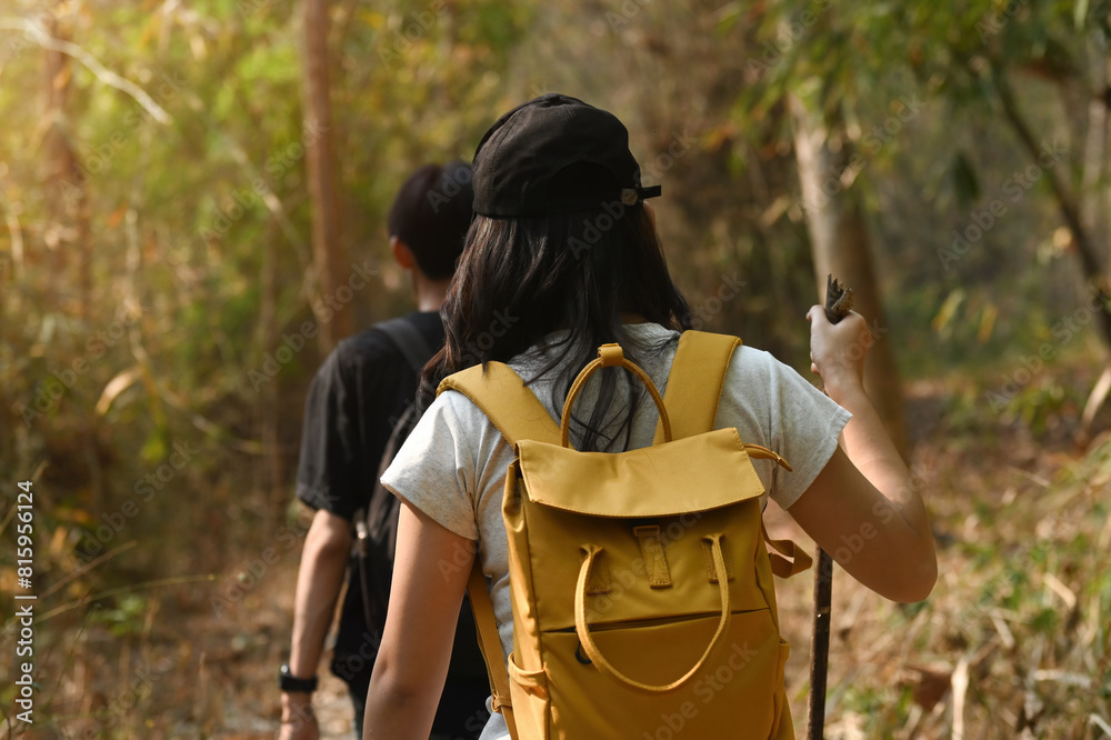 Naklejka premium Rearview of Young transgender woman with backpack trekking with her boyfriend in the forest