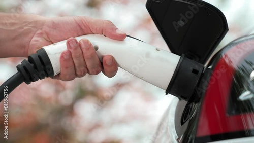 Closeup hand recharging battery for electric car during road trip travel EV car in autumanl season natural forest or national park. Eco friendly travel during vacation and holiday. Exalt photo