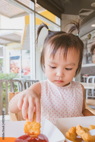 Cute asian girl eating Chicken Nugget by self. Background. Copy space.