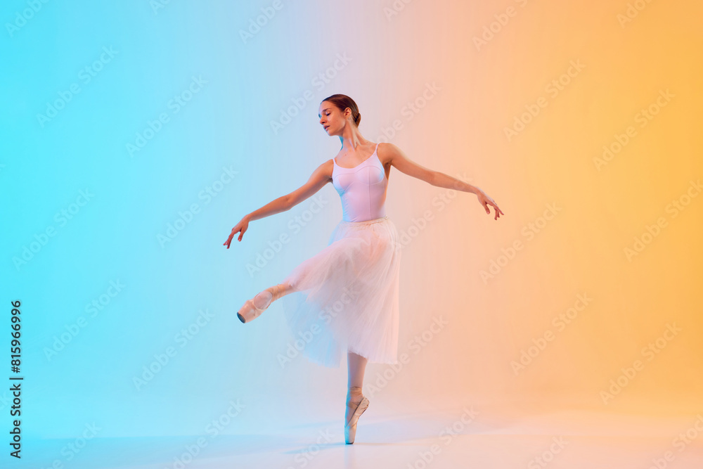 Young ballerina in white tutu an pointe practicing dance moves in neon light against blue-orange gradient background. Concept of art, movement, classical and modern fusion, beauty and fashion. Ad Young ballerina in white tutu an pointe practicing dance moves in neon light against blue-orange gradient background. Concept of art, movement, classical and modern fusion, beauty and fashion. Ad