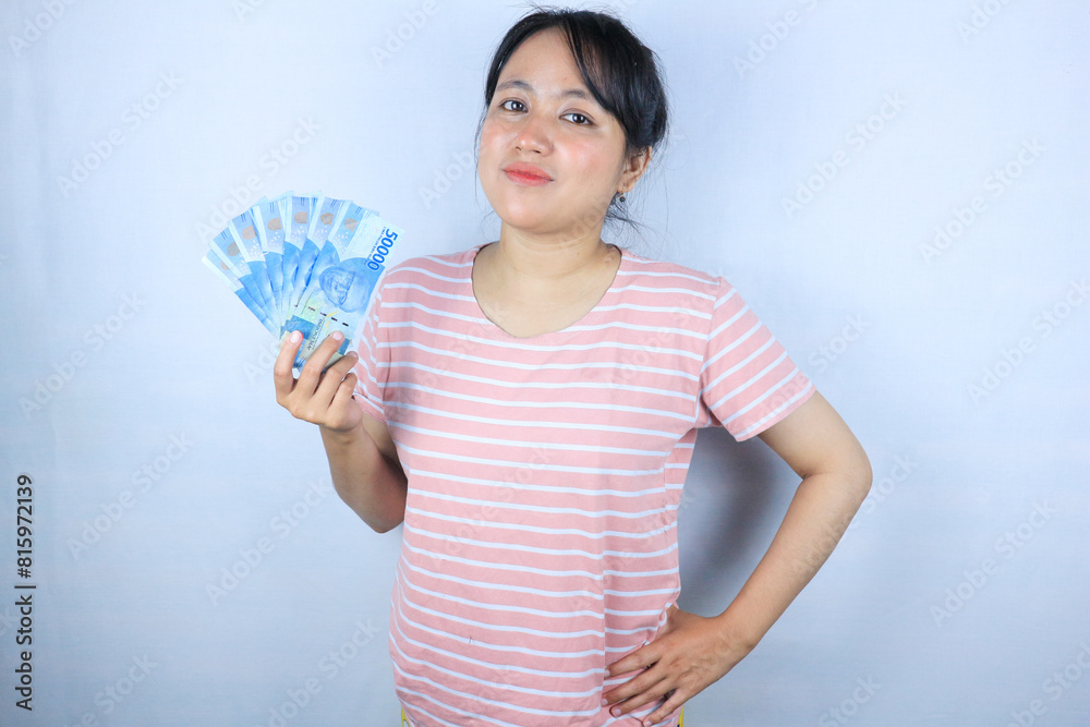 Portrait of a young asian woman holding cash money bills smiling on white background Portrait of a young asian woman holding cash money bills smiling on white background