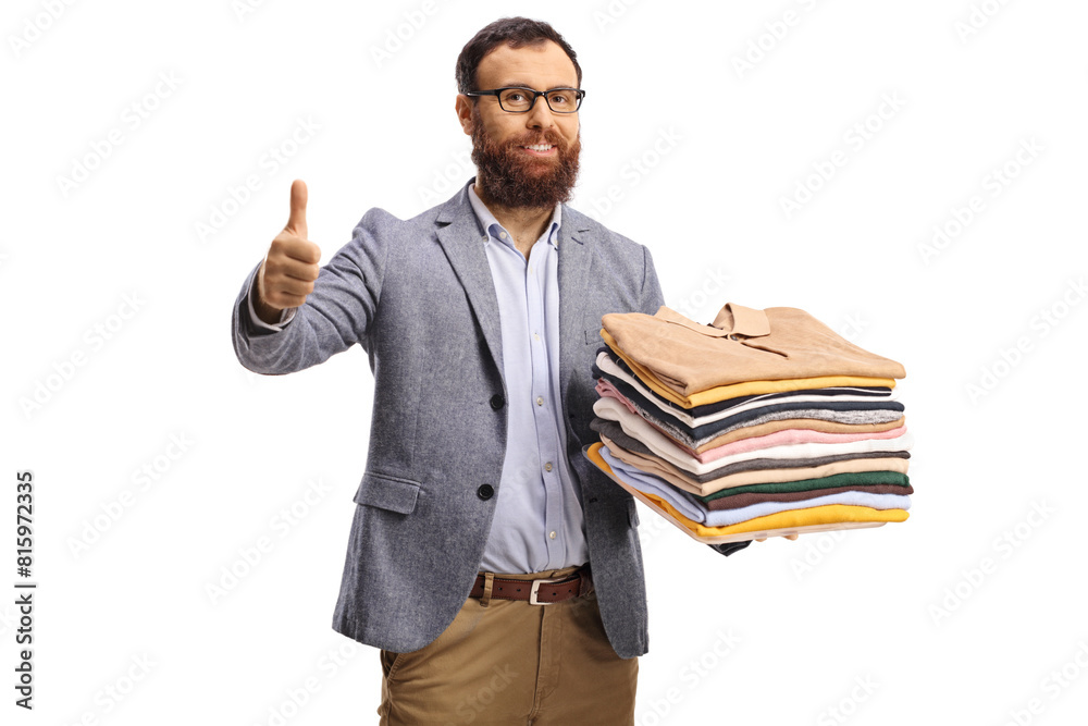 Bearded man with a pile of folded clothes smiling at camera and gesturing thumbs up Bearded man with a pile of folded clothes smiling at camera and gesturing thumbs up